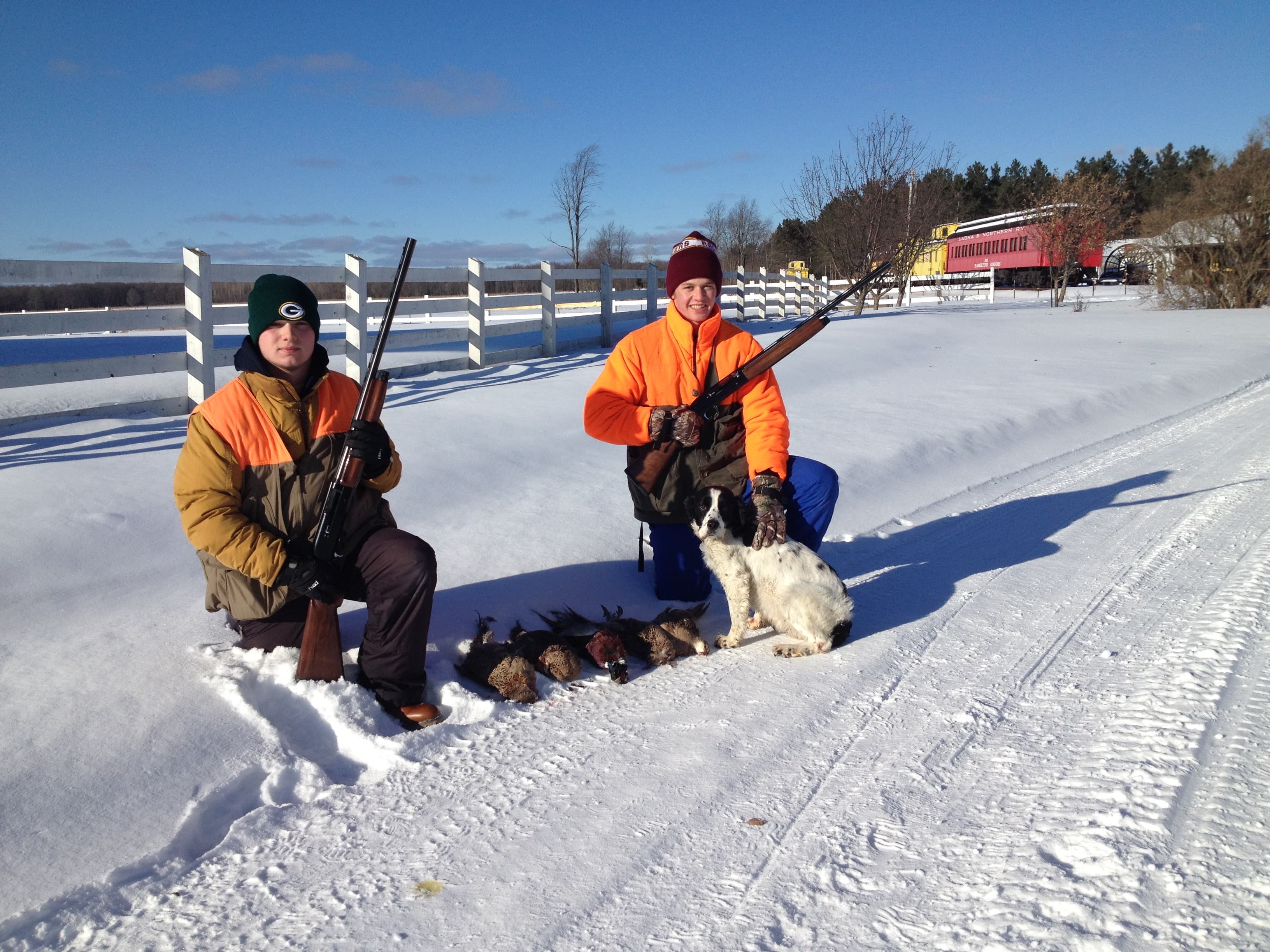 Two hunters with birds and dog after a winter hunt